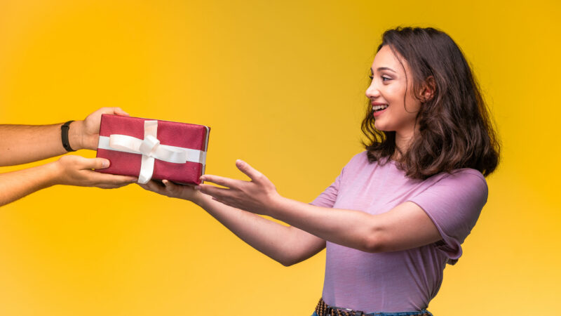 Young girl taking a gift box from her friend at her anniversary. High quality photo
